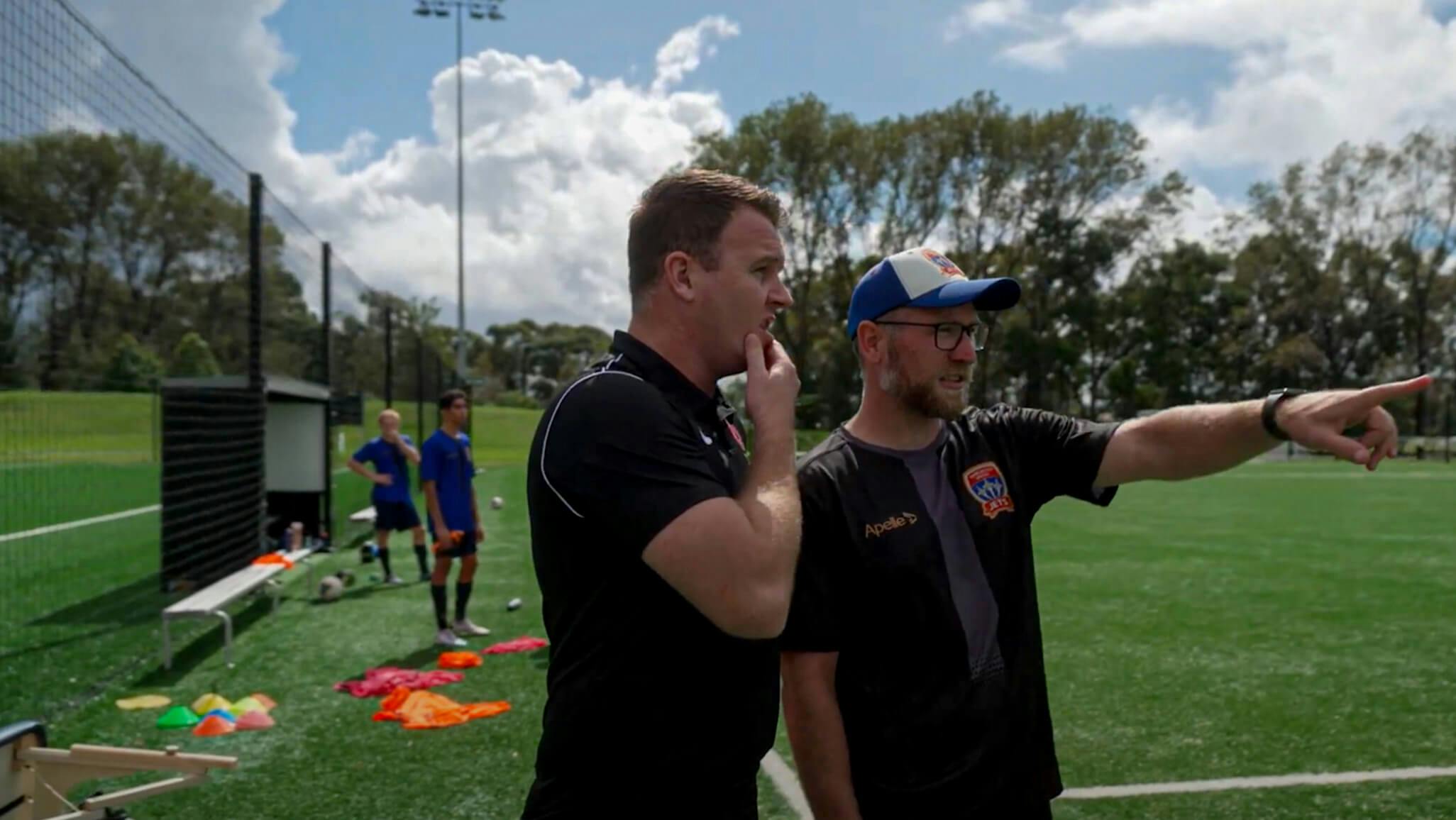 Coaches from Northern NSW engaged in a discussion and pointing at something on the field