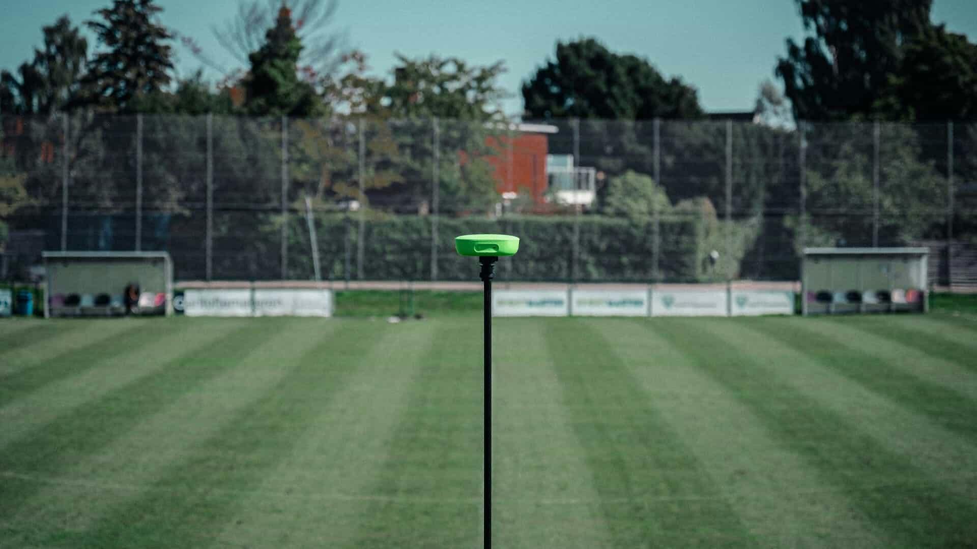 A photo of an empty football field with a tripod and Veo camera mounted on it, showcasing the world's first portable AI sports camera